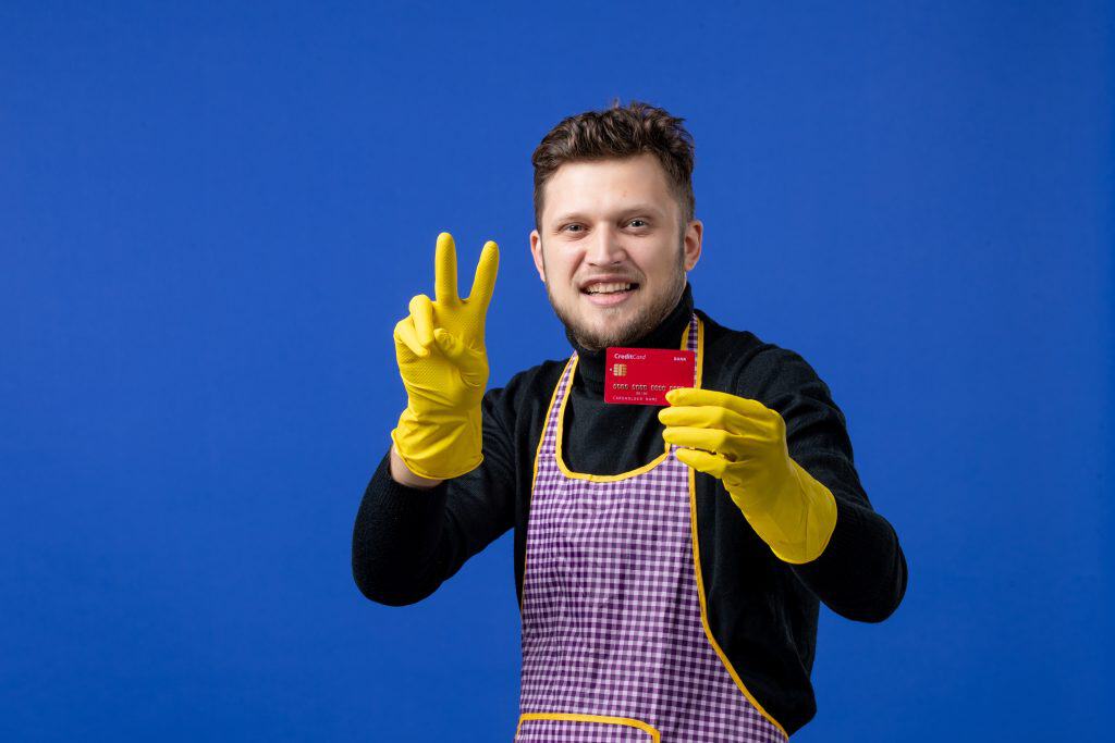Clendo employee wearing yellow gloves and standing in front of a blue backdrop is holding a credit card signifying fixed quote