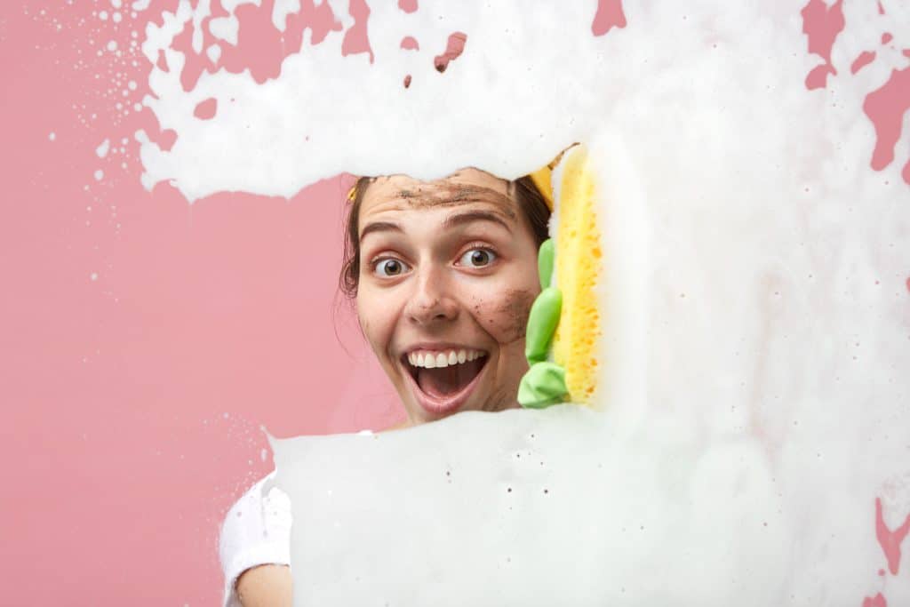 Clendo female cleaner happily cleaning foam with a sponge representing stress free cleaning for our customers